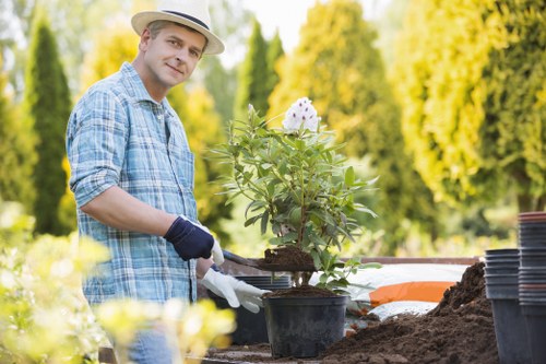Operative wearing full PPE while trimming a residential hedge